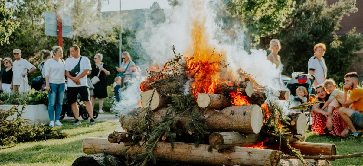 A group of people enjoying an outdoor bonfire during the day in a park setting.
