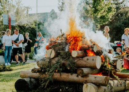 A group of people enjoying an outdoor bonfire during the day in a park setting.